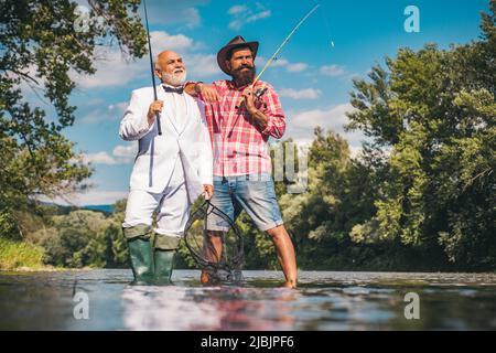 Pêcheurs hommes amis et truite trophée. Père et fils de pêche. Générations hommes pêche dans la rivière. Banque D'Images