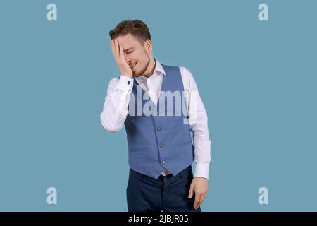 Jeune homme beau avec barbe en chemise blanche et veste bleue debout sur fond bleu est confus et prodiges. Imprécis avec doute, penser gesticler avec les mains. Concept réfléchi. Banque D'Images