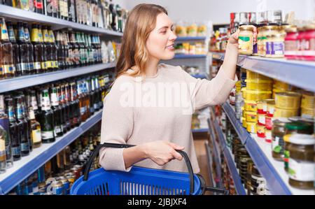 Femme choisissant des produits conservés dans un magasin de nourriture Banque D'Images