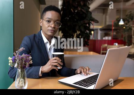 Femme d'affaires sérieuse et concentrée travaillant dans un restaurant d'hôtel, femme afro-américaine voyageant pour un voyage d'affaires Banque D'Images