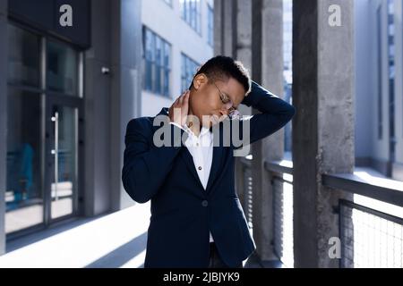 La jeune femme d'affaires a de graves douleurs au cou et au dos, bouleverser la femme afro-américaine hors de ses fonctions Banque D'Images