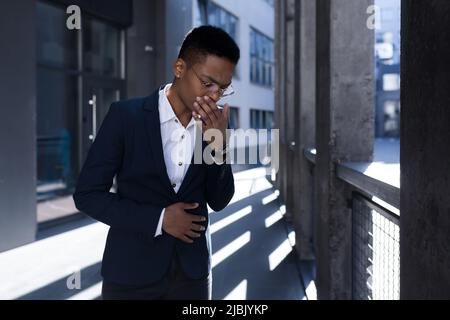 Femme d'affaires afro-américaine près du bureau, se sentant déprimée et toussant mal Banque D'Images