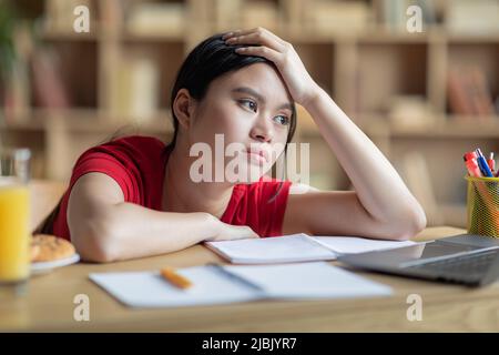 Adolescent frustré fatigué ennuyant asiatique fille étudiant étudier à la maison, regarde l'ordinateur portable dans la chambre à l'intérieur Banque D'Images