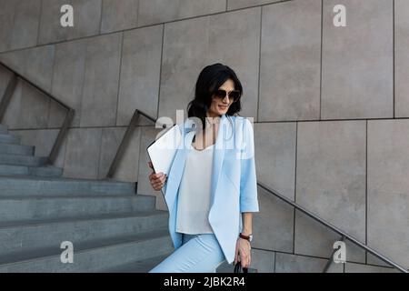 Belle jeune femme d'affaires avec un ordinateur portable dans ses mains marche vers le centre de bureau pour travailler, une réunion d'affaires, parler au téléphone, Banque D'Images