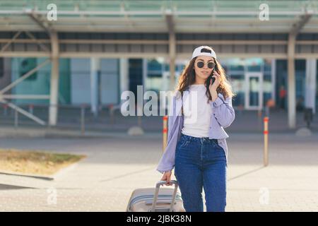 Jeune belle fille femme avec valise et téléphone, appelant quelqu'un, à la recherche d'appeler un taxi, à l'aéroport, est arrivée par avion, dans un ci inconnu Banque D'Images