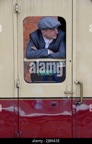 Un homme de vêtements d'époque se penchait par une fenêtre de calèche sur un train à vapeur historique à la gare de Bewdley, Severn Valley Railway, Royaume-Uni Banque D'Images