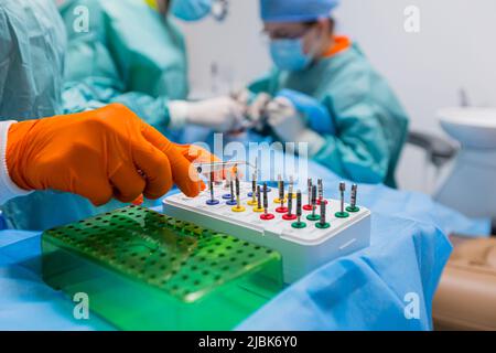 Photo en gros plan des implants dentaires. Dentiste chirurgien et assistant effectuer la chirurgie et le traitement des dents du patient dans le bureau sous forme médicale Banque D'Images