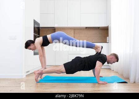 Un jeune couple, un homme et une femme jouent ensemble au sport à la maison sur le tapis, font des exercices, baiser Banque D'Images