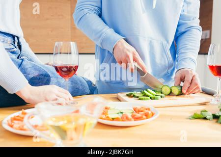 Photo en gros plan des mains d'une femme et d'un homme préparant des aliments, salade sur la table de cuisine, vin, légumes, fruits, Banque D'Images