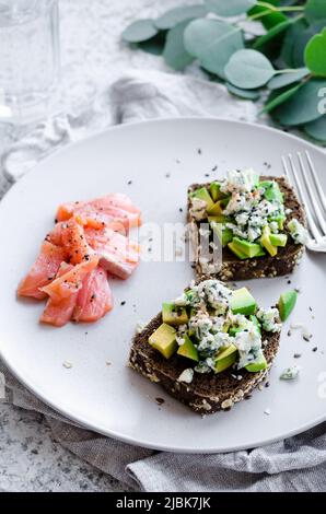 Petit-déjeuner sain avec du saumon et des toasts avec du pain de seigle, de l'avocat et au fromage bleu. Banque D'Images