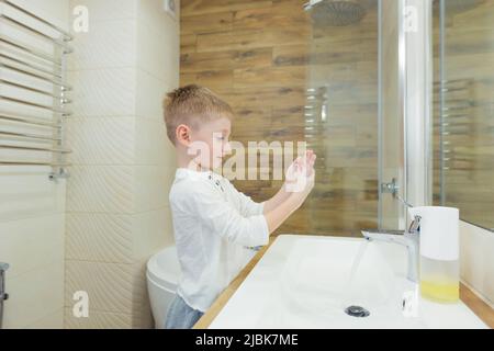 Un petit garçon lave ses mains avec du savon, désinfecte dans la salle de bains, à la maison, au restaurant, à l'hôtel, au centre commercial Banque D'Images