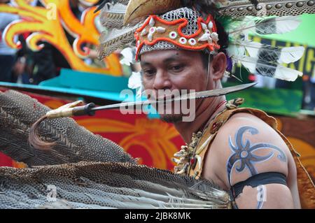 Djakarta, Indonésie - 28 avril 2013 : Un participant au festival Dayak de Djakarta, Indonésie, pose en mordant Mandau, le mach traditionnel Dayak Banque D'Images