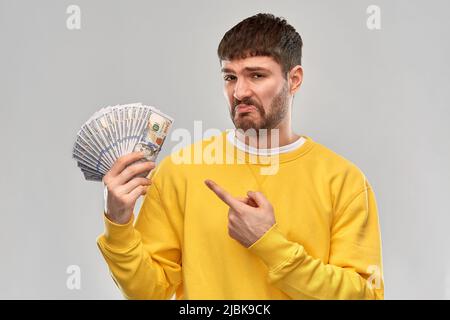 un homme décontent dans un sweat-shirt avec de l'argent dollar Banque D'Images