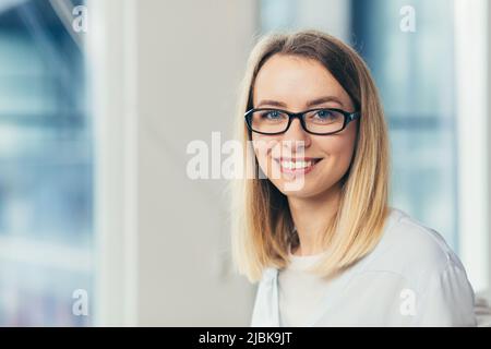 Gros plan portrait de jeune belle femme blonde avec des lunettes, souriant, regardant l'appareil photo Banque D'Images