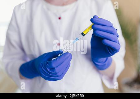 les mains de la femme composent le vaccin dans une seringue, photo de gros plan Banque D'Images