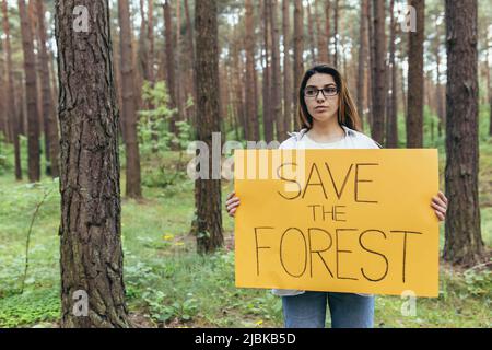 une jeune femme se porte volontaire dans les piquets de bois et tient une affiche à l'exception de la forêt Banque D'Images