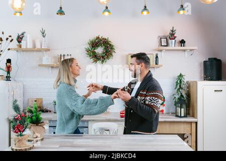 Jeune couple mari et femme heureux de se préparer pour le nouvel an et la fête de Noël, la famille ayant le plaisir de danser dans la cuisine