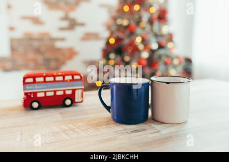 Photo en gros plan de deux coupes de Noël, sur fond de nouvel an, arbre de Noël et lumières colorées, dans la cuisine sur la table Banque D'Images
