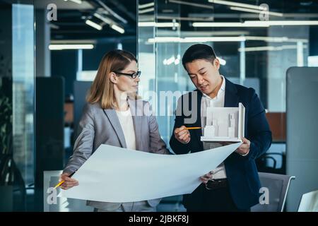 Groupe de jeunes ingénieurs créatifs développeurs discutant d'un nouveau projet en cours de bureau lisant un plan. Le concepteur de l'architecte d'équipe conversations Asian m Banque D'Images