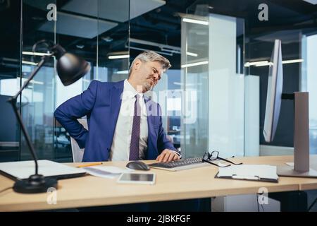 Homme d'affaires ouvrier fatigué travaillant dans le bureau assis à l'ordinateur, l'homme a de graves maux de dos Banque D'Images