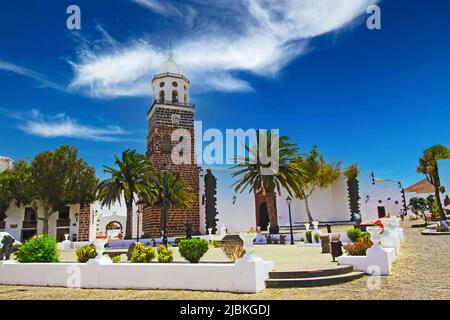 Belle place de la ville des canaries, clocher de l'église en brique rouge, maisons blanches impeccables, jardin des palmiers, ciel bleu d'été - Teguise, Lanzarote Banque D'Images