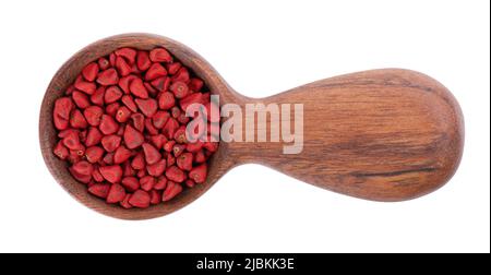 Graines d'annatto en cuillère en bois, isolées sur fond blanc. Graines d'achiote, bixa orellana. Colorant naturel pour la cuisine et la nourriture. Gros plan. Vue de dessus Banque D'Images