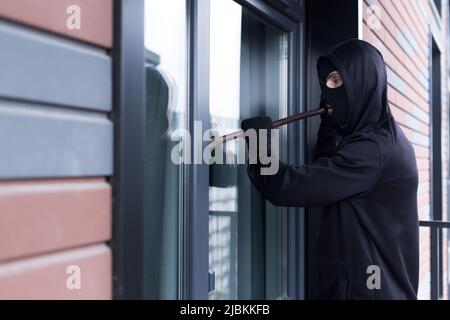 Un cambrioleur essaie de casser la serrure de porte et d'entrer dans l'appartement pour le vol Banque D'Images