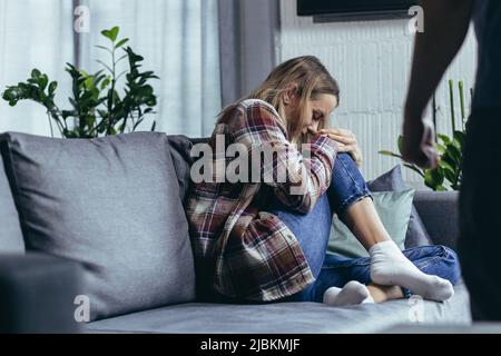Violence domestique, mari en colère criant et battant une femme, photo en gros plan, femme pleurant assis sur un canapé Banque D'Images