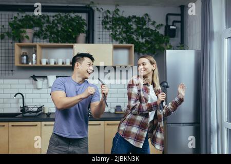 Homme et femme dansant ensemble, s'amusant à la maison, dans la cuisine, une famille multiraciale Banque D'Images