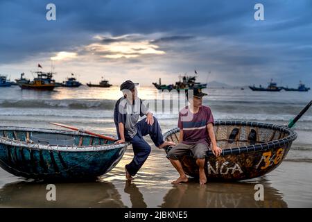 My Khe Beach, Da Nang City, Vietnam - 30 avril 2022 : deux pêcheurs s'assoient et se reposent dans leur panier après un voyage en mer à My Khe Beach, Da Nang City, Banque D'Images