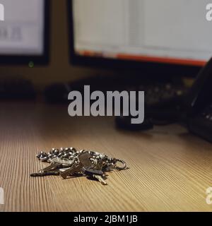 Un tas de clés de la pièce se trouve sur un bureau avec des moniteurs d'ordinateur Banque D'Images