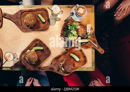 Photographie alimentaire. Vue de dessus des hamburgers servis avec des légumes frais, concombres sur des planches de bois dans un style rustique. Banque D'Images