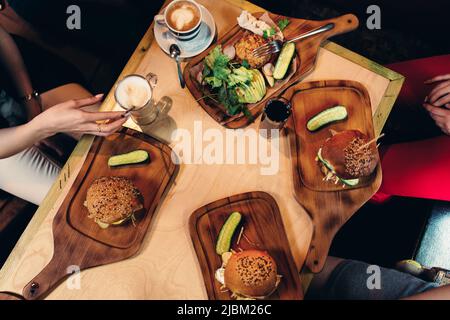 Photographie alimentaire. Vue de dessus des hamburgers servis avec des légumes frais, concombres sur des planches de bois dans un style rustique. Banque D'Images