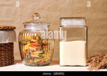 Pâtes colorées et semoule dans les vases de la cuisine avec panier et seigle. Toile de fond de la cuisine traditionnelle avec espace de copie Banque D'Images