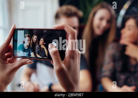 Des femmes prennent des photos avec un smartphone de jeunes amis joyeux, un arrière-plan flou. Banque D'Images