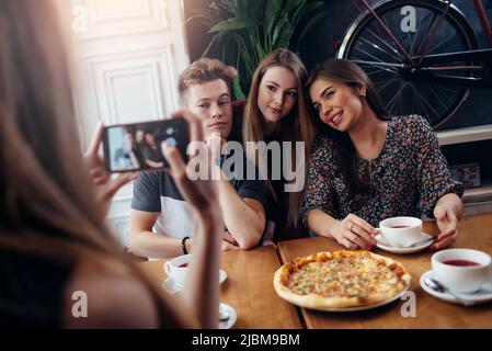 Des femmes prennent des photos avec un smartphone de jeunes amis joyeux. Banque D'Images