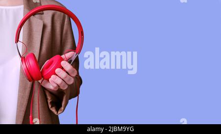 Femme enseignante tenant des écouteurs rouges dans ses mains sur fond bleu, bannière de gros plan Banque D'Images