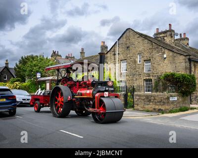 Véhicule à vapeur rouge à l'ancienne et lourd restauré d'époque (cheminée noire, plaque en L, chauffeur) - Burley-in-Wharfedale, West Yorkshire, Angleterre, ROYAUME-UNI. Banque D'Images