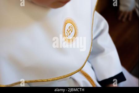IHS symbole chrétien sur un enfant de communion. Christogramme IHS brodé avec un fil d'or sur un alba blanc. Première robe de communion. Banque D'Images