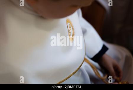 IHS symbole chrétien sur un enfant de communion. Christogramme IHS brodé avec un fil d'or sur un alba blanc. Première robe de communion. Banque D'Images