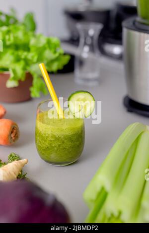 Smoothie vert en verre avec paille et concombre et légumes à l'arrière-plan, détox, végétalien, boisson végétarienne saine aux légumes Banque D'Images