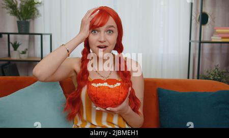 Portrait de la femme à tête rouge assis sur un canapé, manger du pop-corn et regarder la télévision film en série jeu de championnat de film, contenu de médias sociaux en ligne à la maison. Ginger Girl appréciant les divertissements domestiques Banque D'Images