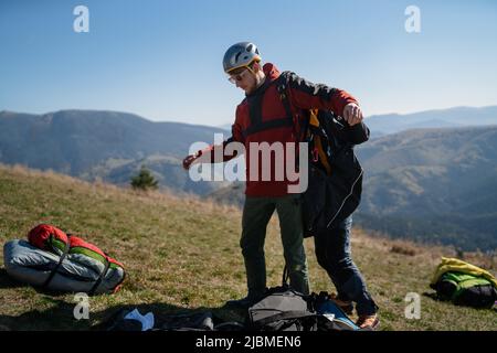 Homme aidant le pilote de parapente à se préparer au vol. Banque D'Images