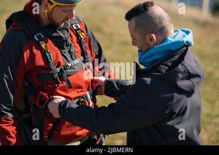 Homme aidant le pilote de parapente à se préparer au vol. Banque D'Images