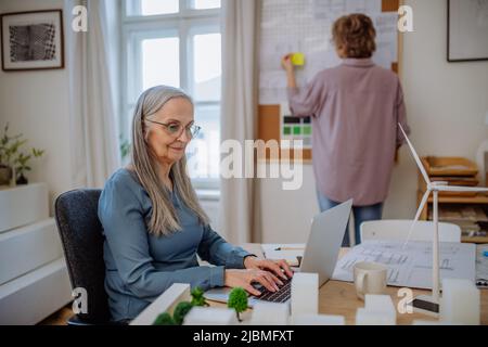 Des femmes matures et heureuses, des éco-architectes travaillant ensemble au bureau. Banque D'Images
