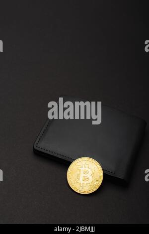 KIEV, UKRAINE - 26 AVRIL 2022 : vue à grand angle du bitcoin doré sur portefeuille sur fond noir Banque D'Images