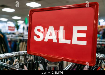Affiche de solde rouge sur le rail des vêtements dans un magasin ou une boutique de grande rue Banque D'Images