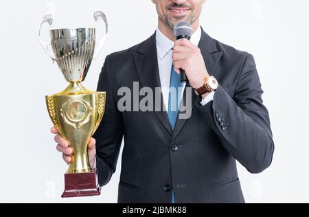 un homme mûr heureux en costume tient la tasse de champion et le microphone isolés sur fond blanc Banque D'Images