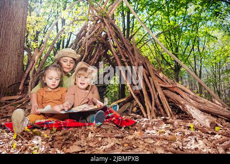 Trois enfants s'assoient avec la carte du trésor pour jouer à la chasse au Trésor Banque D'Images