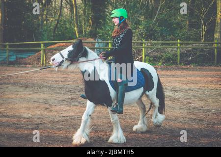 Une adolescente à cheval sur un poney piébald gitan en épi Banque D'Images